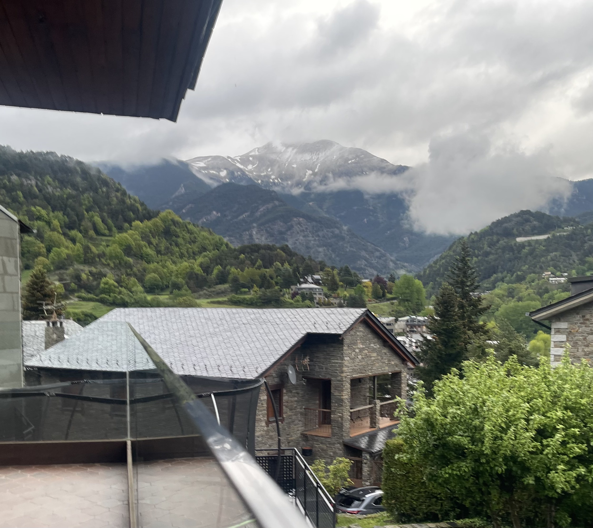 Snow-capped peaks emerging through rain clouds, view from chalet balcony